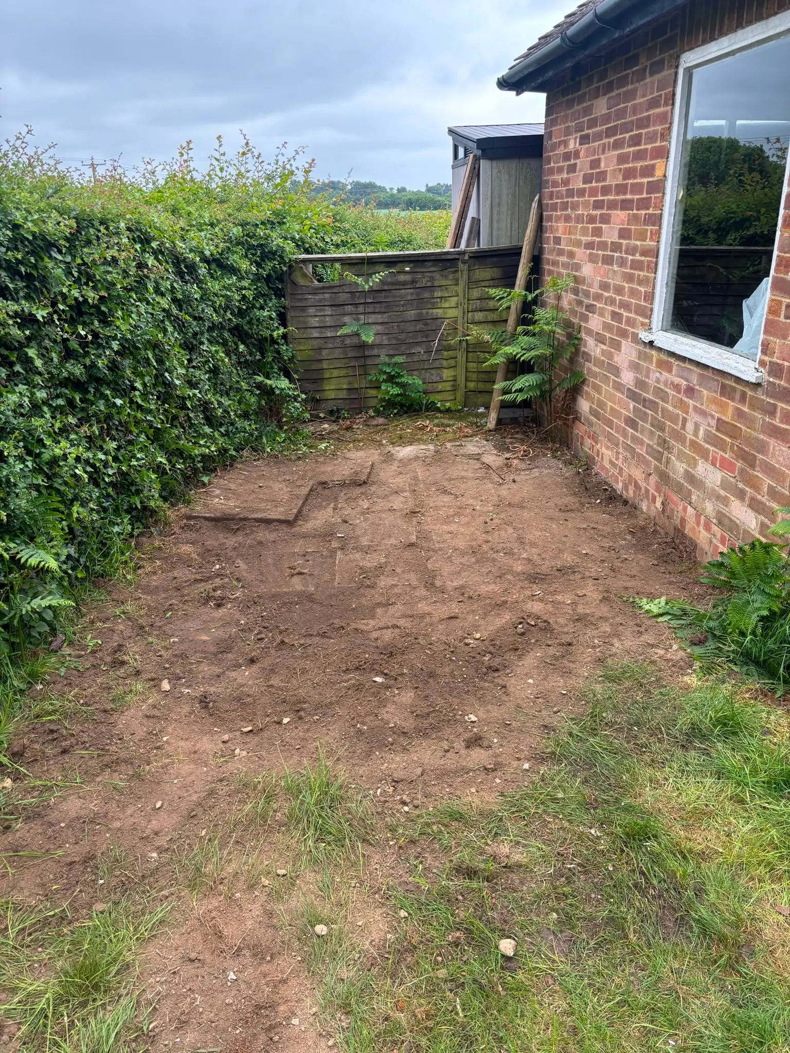 Cleared rear garden after a garden clearance Cleared rear garden area beside a brick residential property.